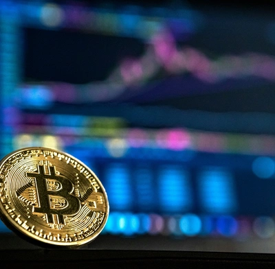 A Bitcoin in front of a  trading screen